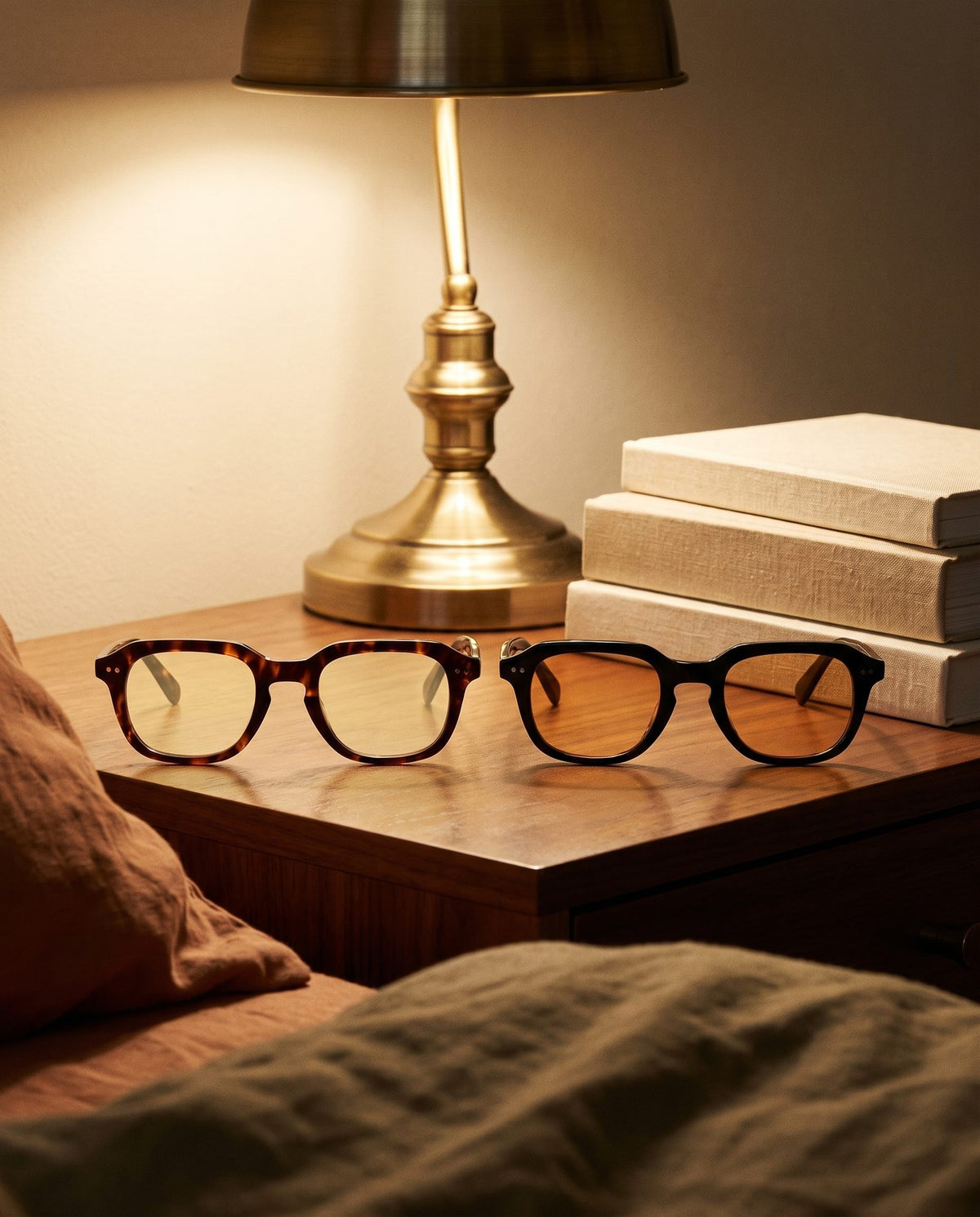 Both pairs folded together on a nightstand by lamplight