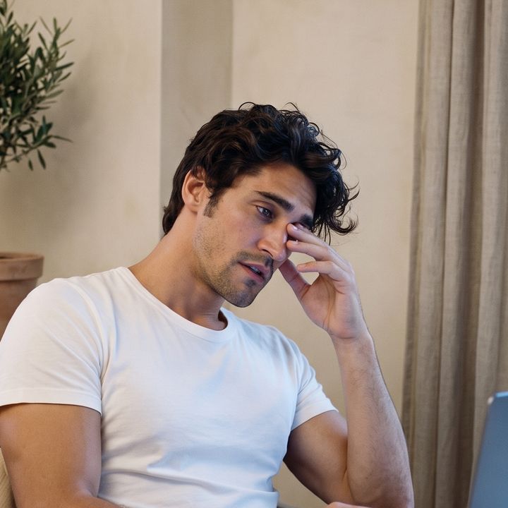 Early evening, slumped at the laptop rubbing his eye